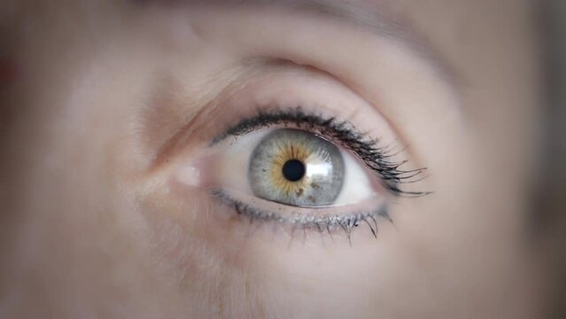 Close up of a woman's grey eye opening in rotating slow motion. Zoom out, shallow depth of field. 