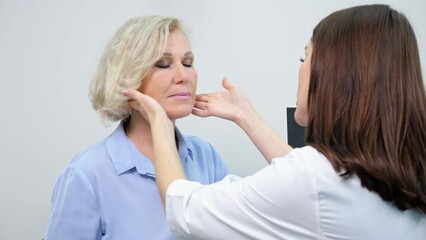 Experienced doctor gives cosmetological consultations to mature woman in beauty clinic. Brunette beautician plans face and neck lifting for joyful patient