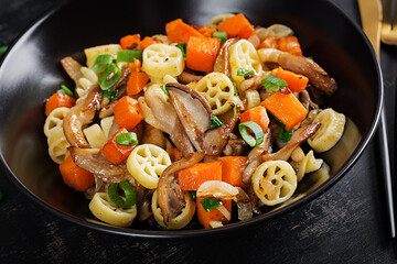 Rotelle pasta gluten free with mushrooms and pumpkin on a dark background. Vegetarian, vegan  food. Italian cuisine.