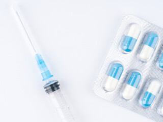 Pills and a syringe on a white background. Closeup