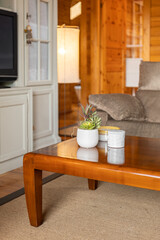 Wooden tea table with candles and a white vase with plants in the interior of the cottage living room
