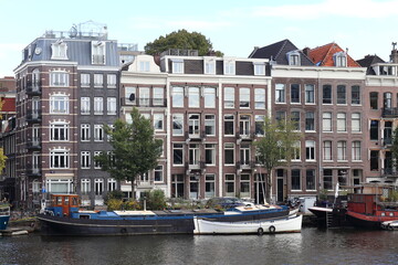 Fototapeta na wymiar Amsterdam Amstel River View with Boats and House Facades, Netherlands