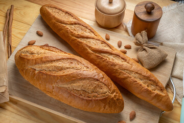 Baked baguette and multigrain loaf bread on brown wooden table ready to serve.