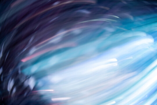 Defocused light motion. Blur radiance. Smeared fluorescent beams. Bokeh luminous neon purple blue white color glowing rays texture on dark black abstract free space background.