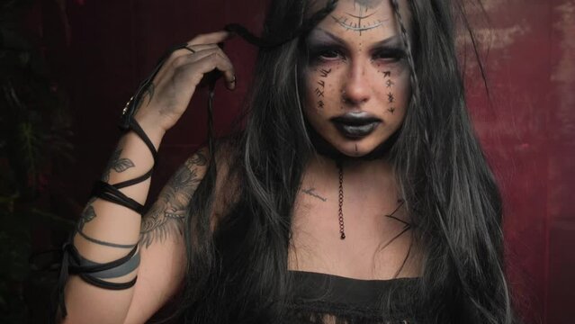 Portrait of a witch girl with black eyes on a red background in the smoke.