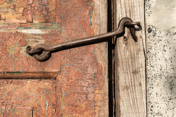 Shabby surface. Closed door. Rustic wooden texture. Grunge board gate with cracked surface of orange paint and metal hook copy space for text logo.