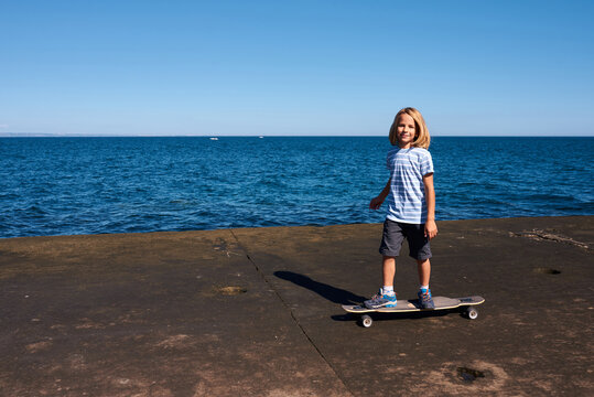 Boy riding a longboard on a pier at sunny day - Powered by Adobe