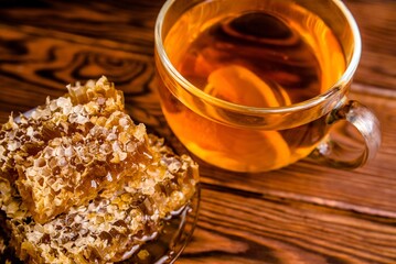 honey in honeycombs and a mug of tea on a brown wooden background 