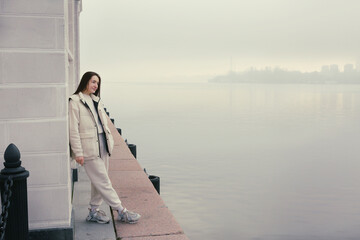 brunette girl with long hair in white jacket full body portrait on foggy landscape background