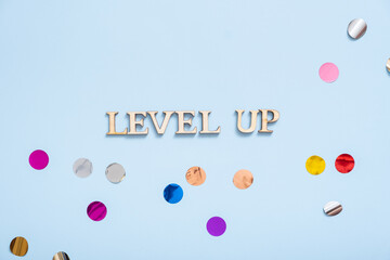 Level up wooden inscription on a colored background with tinsel. Achievement concept