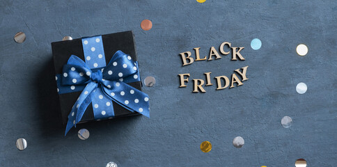 Black Friday text with black gift box flat lay on dark cement background. Top view
