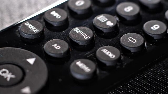 watching tv close-up buttons on the TV remote with the subtitle button in the center 
Super macro of television buttons on the TV remote control. Super macro high quality 4k video.