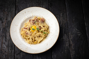 delicious pasta with cheese, egg, greens, sauce in a restaurant
