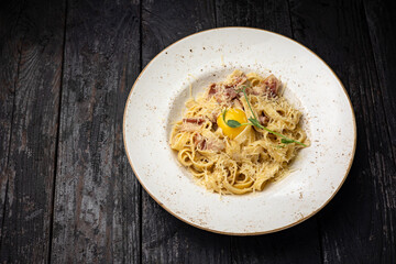 delicious pasta with cheese, egg, greens, sauce in a restaurant
