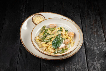 delicious pasta with cheese, salmon, greens, sauce in a restaurant
