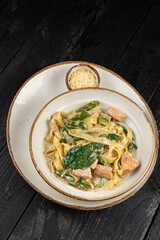 delicious pasta with cheese, salmon, greens, sauce in a restaurant
