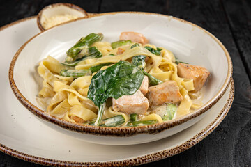 delicious pasta with cheese, salmon, greens, sauce in a restaurant
