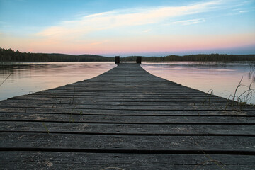 Fototapeta na wymiar Wooden jetty reaching into a swedish lake at blue hour. Nature from Scandinavia