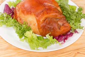 Boiled-smoked pork knuckle on the lettuce leaves on dish