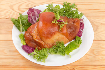 Boiled-smoked pork knuckle on the lettuce leaves on dish