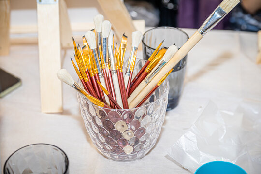 Various paint brushes in the glass jar on the table
