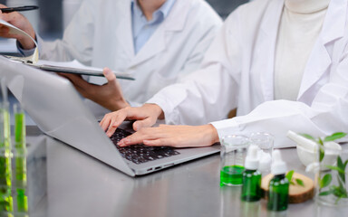 Scientists using laptop for record 
the result of laboratory eco or natural cosmetic, medicine, Skin care, organic make-up, beauty treatment and essential oil experiment or research and development.