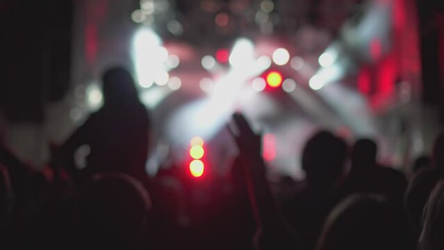 Blurry view of music festival fans and flashing red and white lights on stage, live concert
