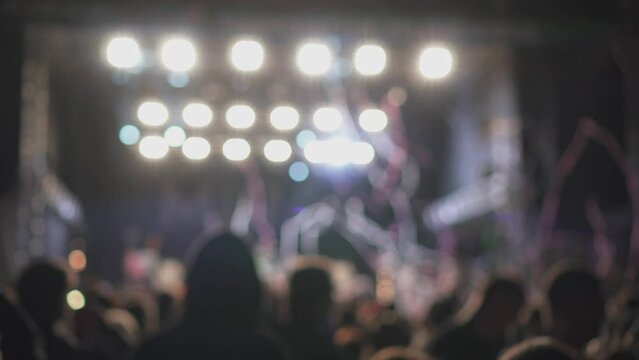 Confetti and flashing lights during live performance or concert above fans of music festival, blurry abstract view