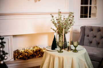 A set table in the living room near the fireplace. Romantic New Year's atmosphere by the fireplace. New Year interior decor in the house.