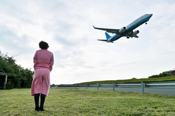 Fototapeta na wymiar Woman looking at the plane in the sky