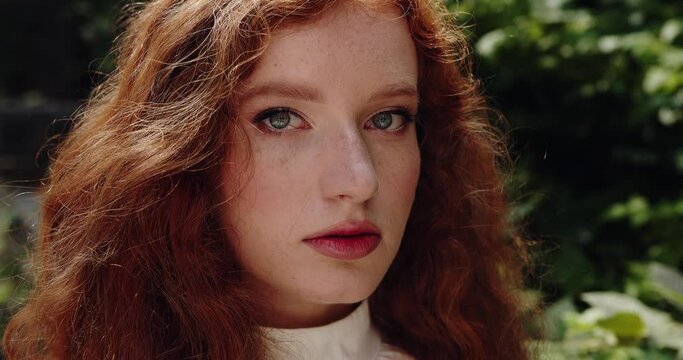 Red-haired foxy woman with natural makeup and green eyes looking at the camera
