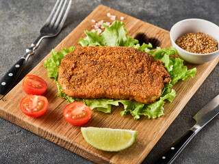 Breaded pork cutlet with cherry tomatoes, mustard and lemon.