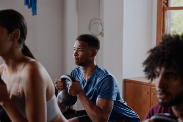 Three multiracial young adults doing kettlebell squats at the gym