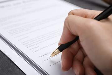 Woman signing last will and testament at grey table, closeup - obrazy, fototapety, plakaty