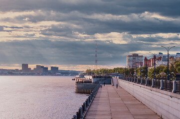 Obraz premium View of the embankment of the city of Blagoveshchensk, Russia, against a stormy sky with gray clouds before the rain. Thunderclouds in the sky. Across the Amur River is the city of Heihe, China
