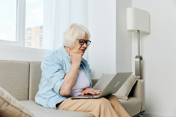 an elderly lady looks at a laptop monitor showing her fist while talking via video link while at...