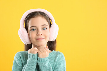 Cute girl wearing stylish earmuffs on yellow background. Space for text