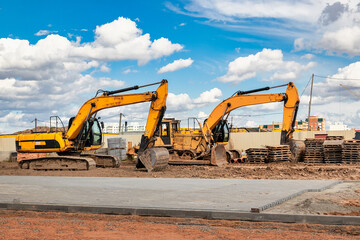 Powerful excavators at a construction site against a blue cloudy sky. Earthmoving construction...