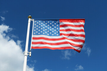 Obraz premium American flag waving on a blue sky background.