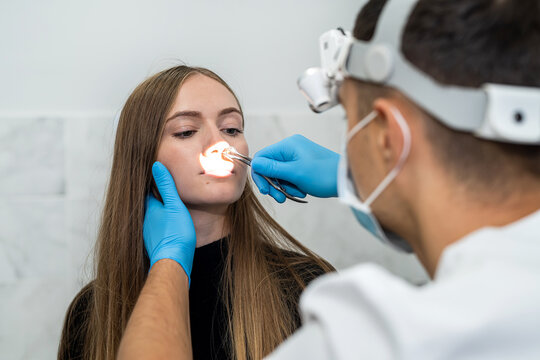 Male Otolaryngologist Examines The Nose Of A Female Patient Before A Nasal Endoscopy Procedure