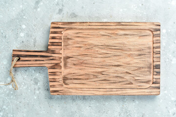 Fototapeta premium Cooking concept. Wooden kitchen board on a gray stone background. Top view. Free space for your text.
