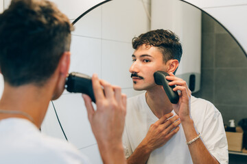 young adult man shaving in bathroom