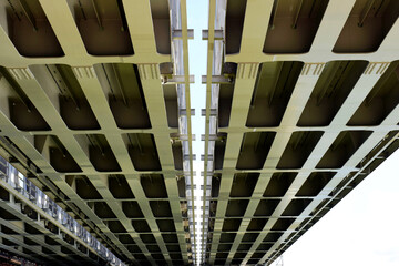 Obraz premium Steel railway bridge underside view. heavy steel girders and beams. strong diminishing perspective view. engineering and transportation concept. industrial design. span bridge. low angle view.