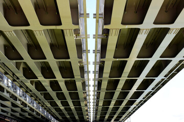 Steel railway bridge underside view. heavy steel girders and beams. strong diminishing perspective view. engineering and transportation concept. industrial design. span bridge. low angle view.