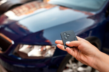 Man thumb presses button on remote control key removing alarm signal  bright car alarm light