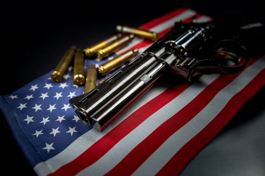 Many yellow bullets and a revolver gun on the flag of United States isolated on black table.