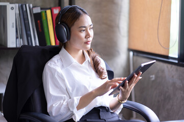 Relaxed businesswoman listening to music in headphones at work break, a young smiling employee...