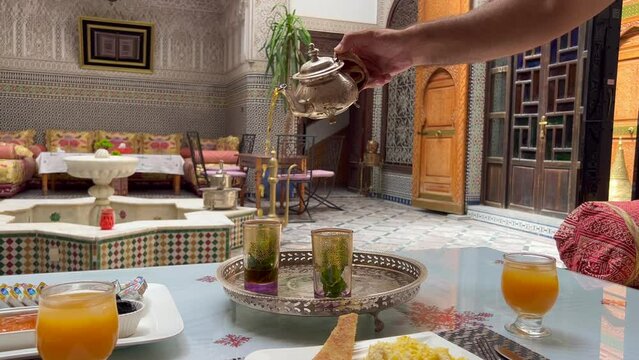 Man pouring mint tea into a Moroccan glasses