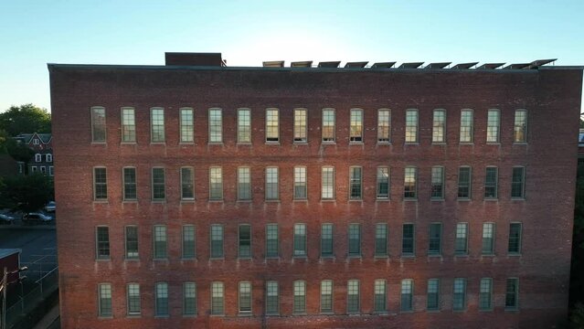 Rising aerial shot of brick industrial building. Reveal of solar panels collecting sunlight on the roof. Environmentalism theme.