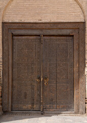 Closeup view of beautiful traditional wooden door of madrasa with floral and geometric carving design, Hisor or Hissar, Tajikistan